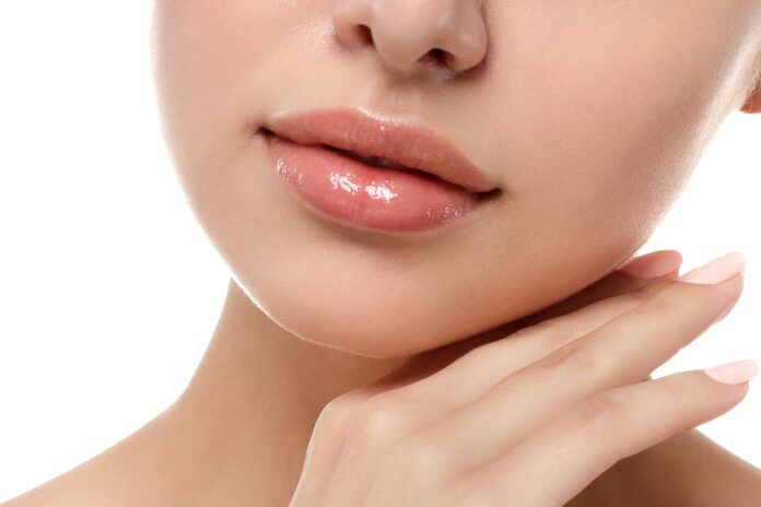 Close up view of young beautiful caucasian woman touching her face isolated over white background. Lips contouring, SPA therapy, skincare, cosmetology and plastic surgery concept