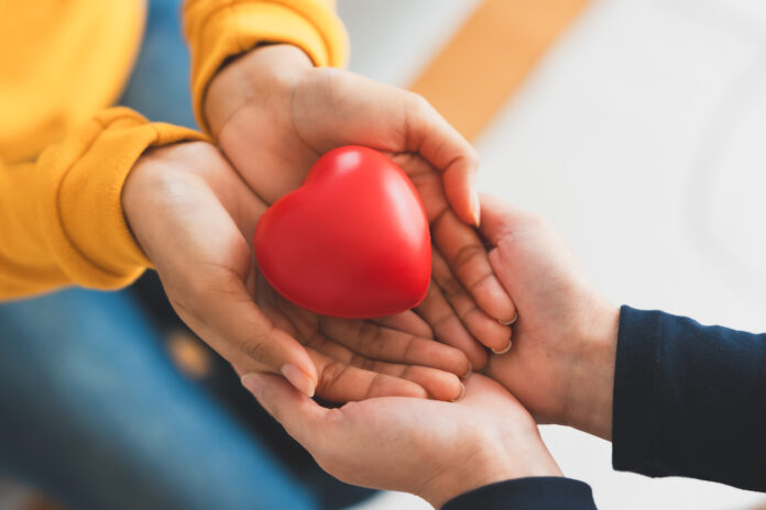 Closeup view of red heart on woman and man hands. Healthy and valentines day concept